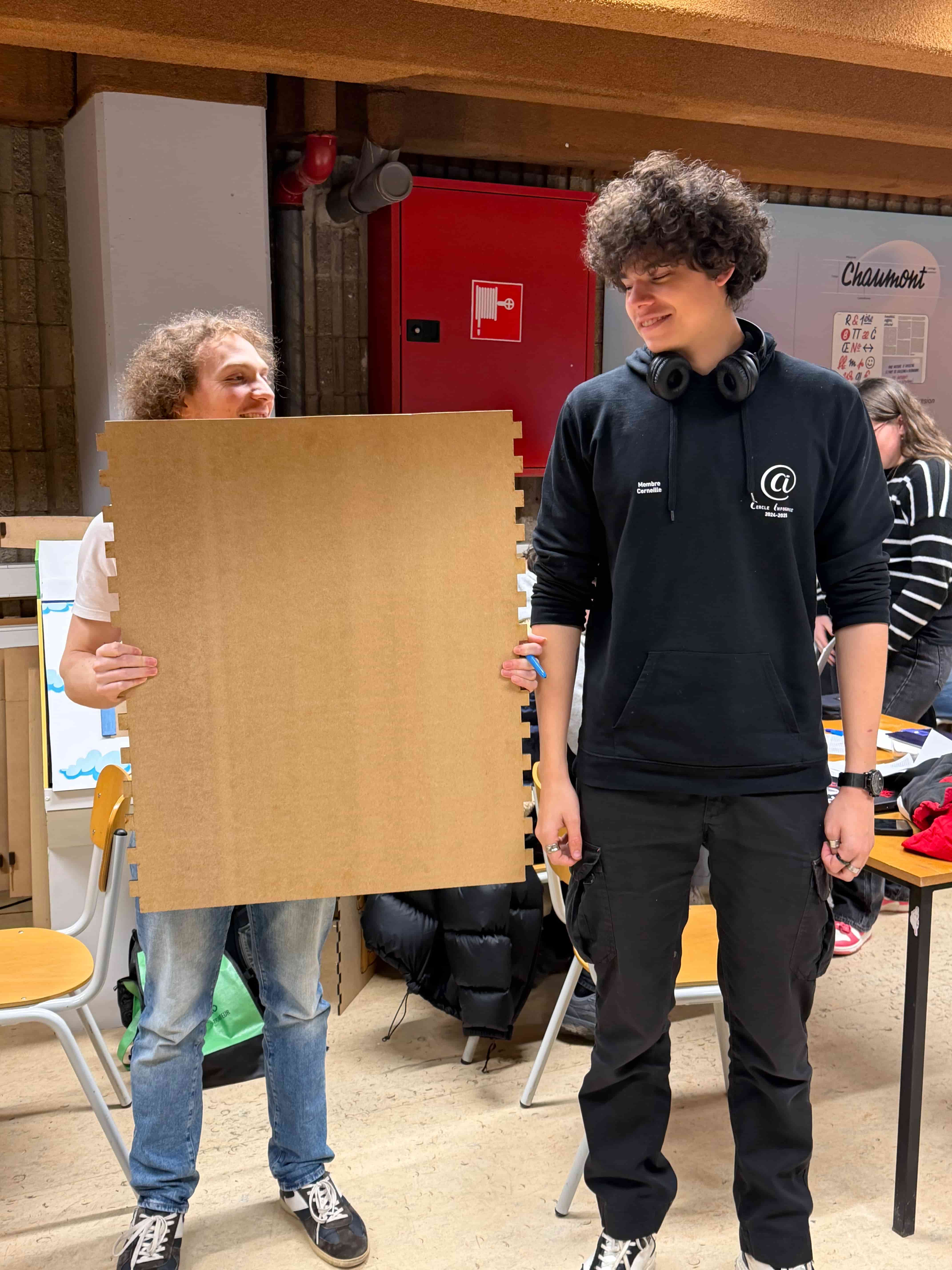 photo de dylan qui tient une planche en bois devant lui et nathan qui se tient debout à coté